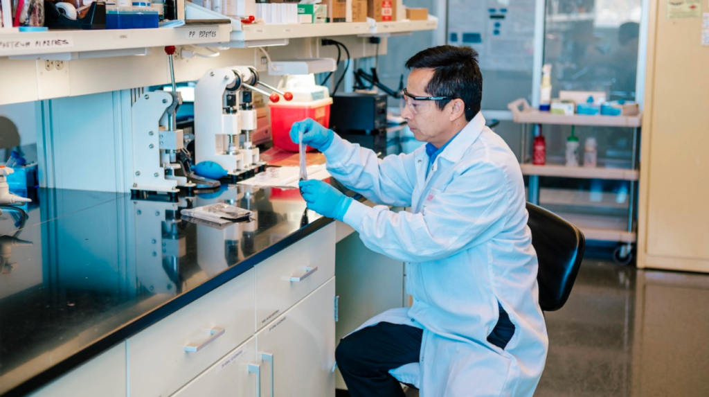 UNCG professor Jianjun Wei pours biochar into a vial for testing